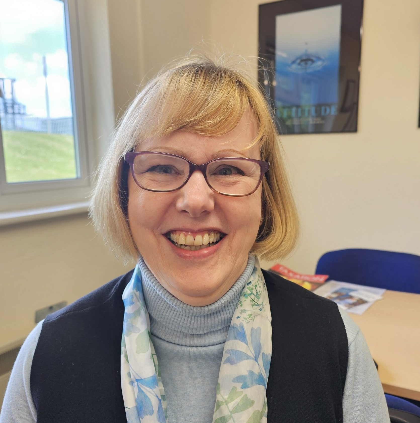 Headshot of smiling woman in glasses with bobbed blonde hair
